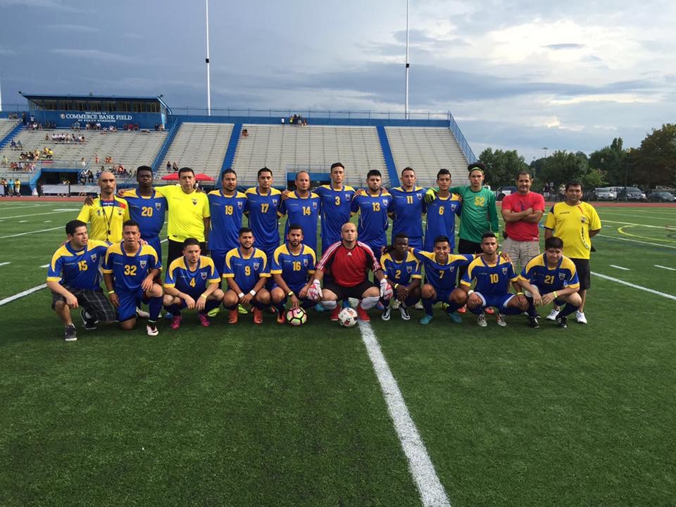 A soccer team in blue and yellow kits posing together on the field at Foley Stadium