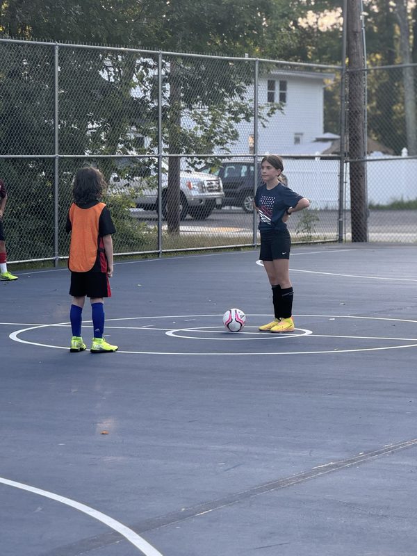 Two players facing off at midfield with the ball between them on an outdoor court